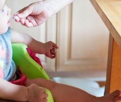 a baby being fed by hand in his high chair