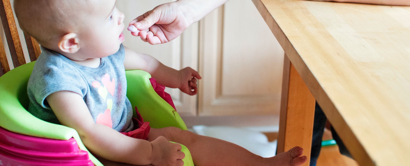 a baby being fed by hand in his high chair