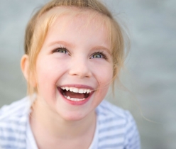 girl with blue eyes looking up and smiling showing her white teeth