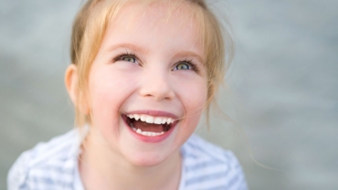 girl with blue eyes looking up and smiling showing her white teeth