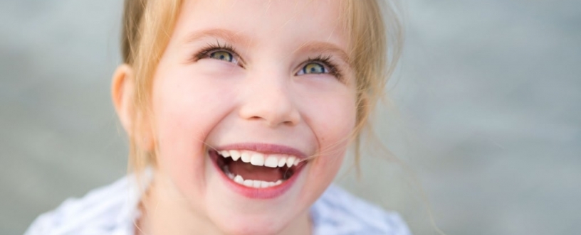 girl with blue eyes looking up and smiling showing her white teeth