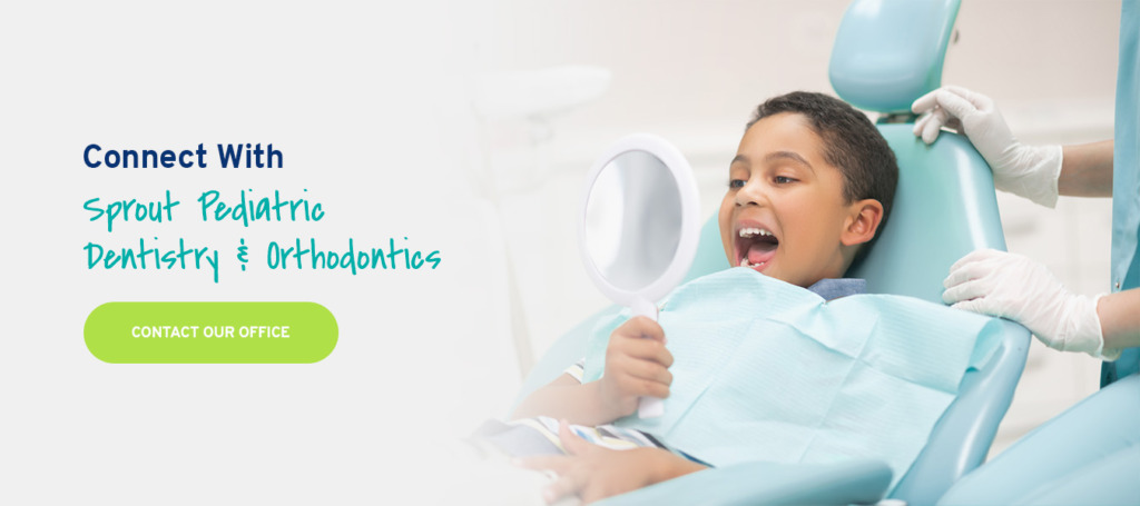 Child looking at his teeth in a mirror in a dentist's chair.