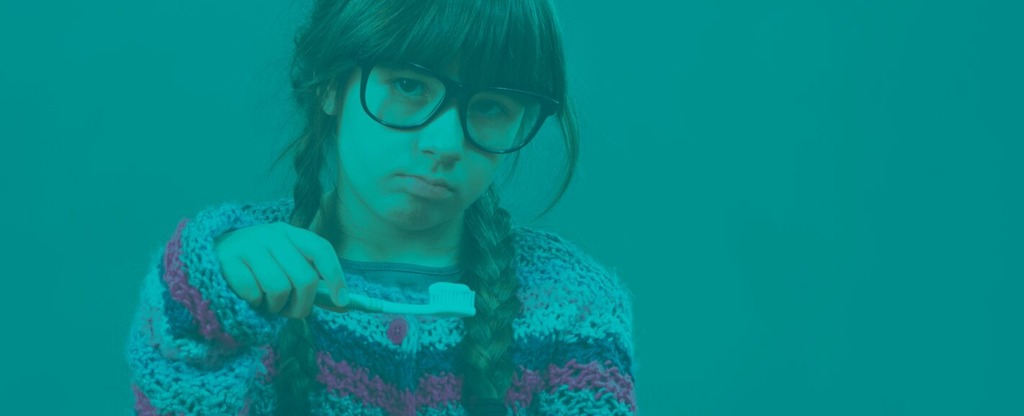 Child looking upset and frowning while holding a toothbrush